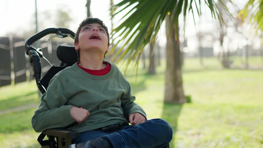 Disabled child looking up in wheelchair in park