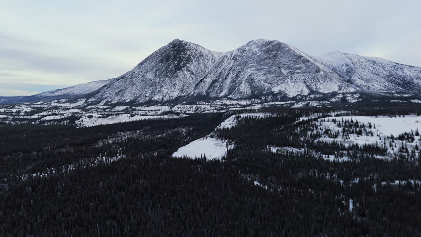 Wintry Landscape Of Snowy Mountains And Spruce Forest Near Takhini River In Yukon, Canada. wide drone shot