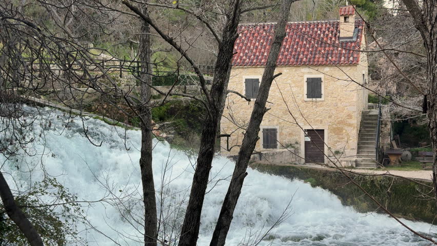 Fast foamy river is flowing past old stone watermill in Krka National Park, Croatia