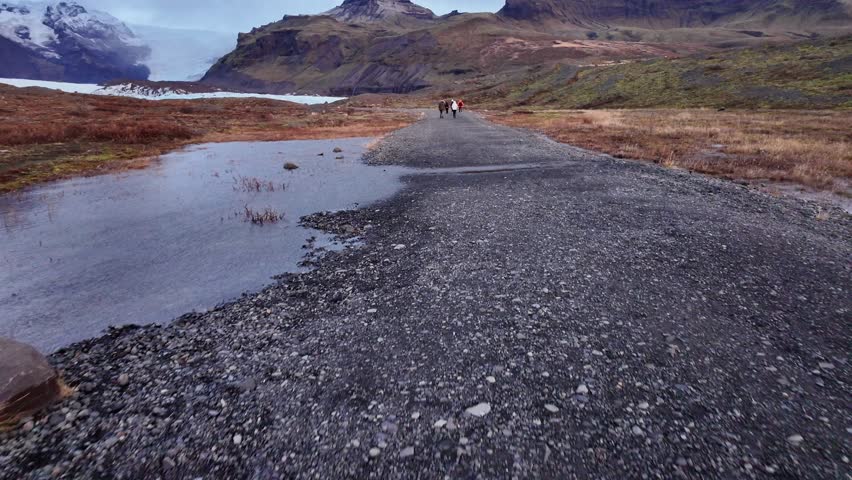 People walking along the Vatnajokull ice cap during a cloudy daytime in Iceland