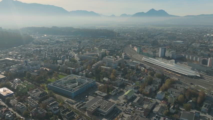 Salzburg Drone Aerial, Austria. Aerial View of Central Train Station and Cityscape and misty mountains