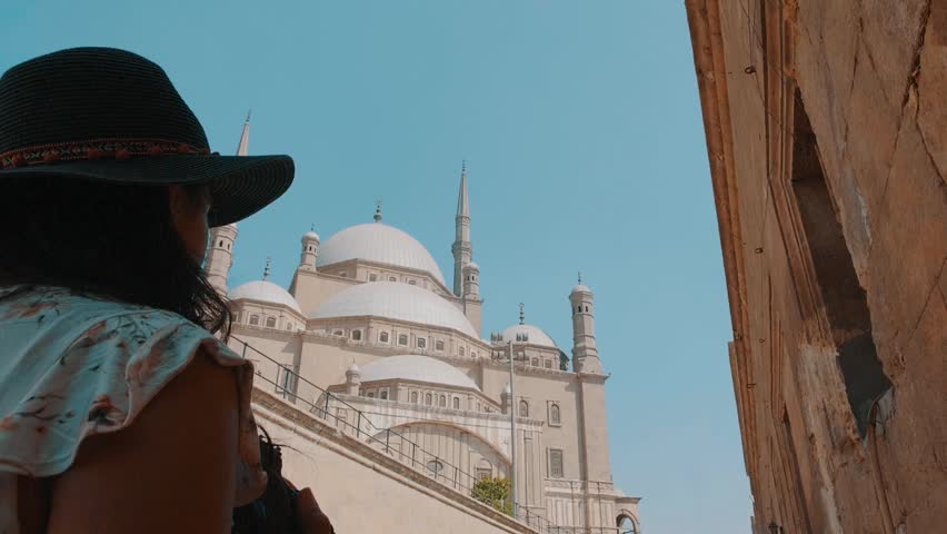 A captivating image of a woman gazing in awe at the Mosque of Muhammad Ali in Cairo, Egypt, showcasing the grandeur of the architectural masterpiece and the sense of wonder.