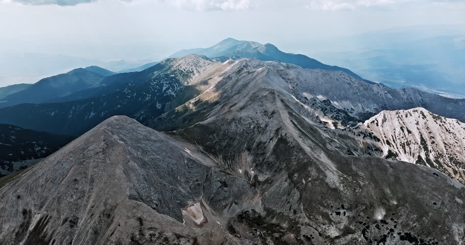 Majestic peaks rise above rugged valleys. Remote highlands, scattered lakes, textured slopes capture raw beauty unspoiled mountain terrain. Rolling ridgelines create dramatic depth. Pirin, Bulgaria