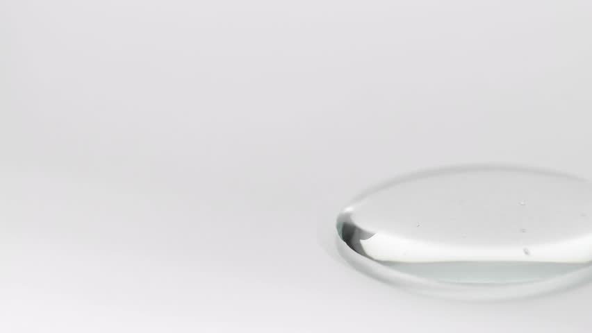 Liquid serum for face and hair dripping on table, cosmetic background macro.