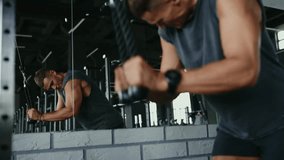 Determined man in a sleeveless shirt using a cable machine in the gym, focusing intensely on his workout for upper body strength and fitness. Young Man Working Out on Cable Machine in Modern Gym - Powered by Shutterstock - Get 15% off with code: PIKWIZARD15