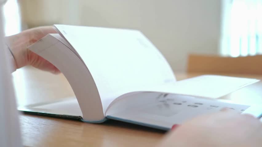 A focused individual immerses themselves in a large book, pages flipping swiftly in a tranquil setting. Natural light enhances the atmosphere, encouraging a deep exploration of knowledge.