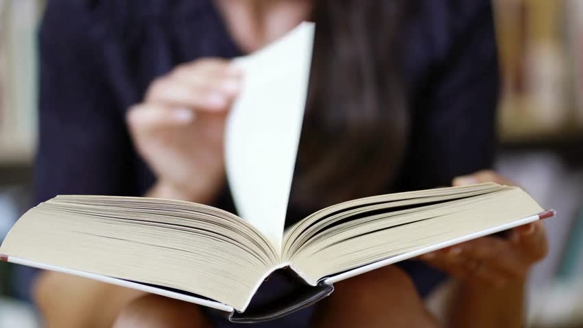 A person is deeply engaged with a book in a cozy library. The atmosphere is serene, promoting focus and learning. Bookshelves in the background suggest a wealth of knowledge.