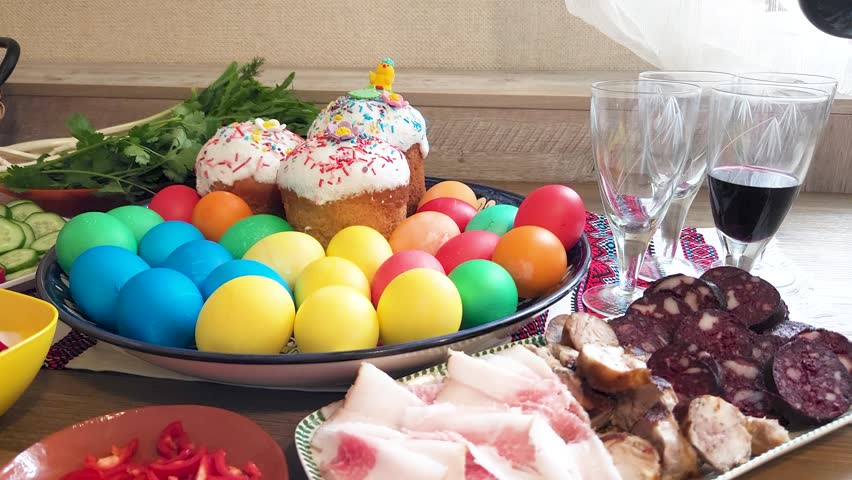 Easter - festive table with Easter cake, craft sausages, colored eggs, lard, cut vegetables and Cahors in glasses on a Ukrainian towel