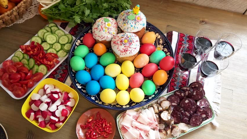 Easter - festive table with Easter cake, craft sausages, colored eggs, lard, cut vegetables and Cahors in glasses on a Ukrainian towel