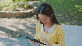 Asian Woman Working outdoors in the park. Professional on a Video Call, exploring Hybrid Work Opportunities in a Peaceful, Virtual Meeting and Online Learning. Hybrid work lifestyle concept - Powered by Shutterstock - Get 15% off with code: PIKWIZARD15