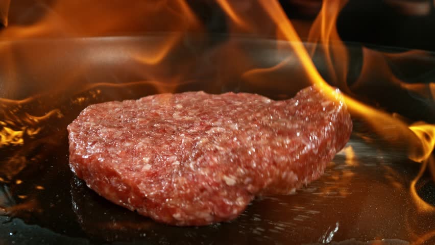 Super Slow Motion of Flying Raw Beef Hamburger Minced Meat on Pan with Fire. Filmed on High Speed Cinema Camera, 1000 fps.