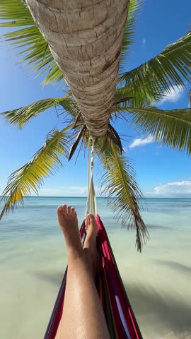A woman's feet in a hammock on a tropical beach, rest and relaxation on vacation	