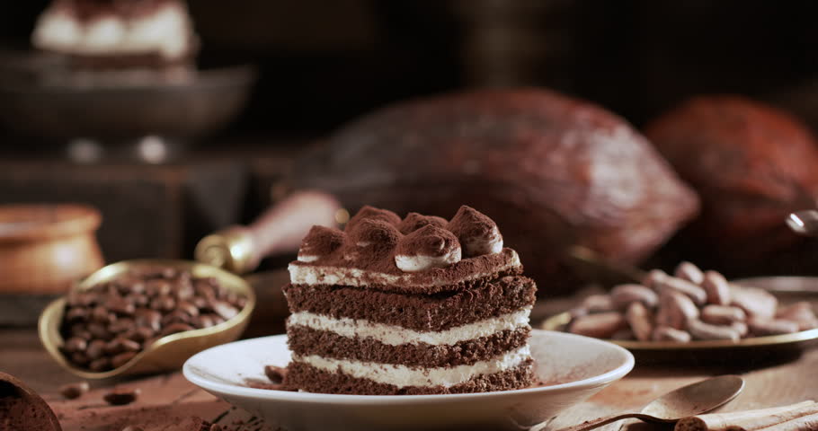 Close-up shot of a male baker's hands carefully preparing a homemade tiramisu cake. Hands gently sprinkle cocoa powder over the creamy mascarpone layer.