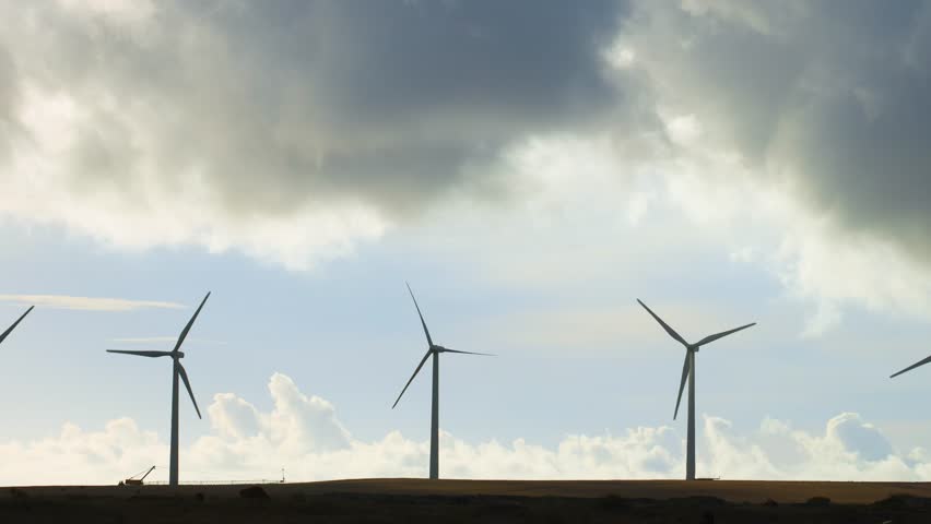 Row of wind turbines near the ocean in Hawaii at sunset