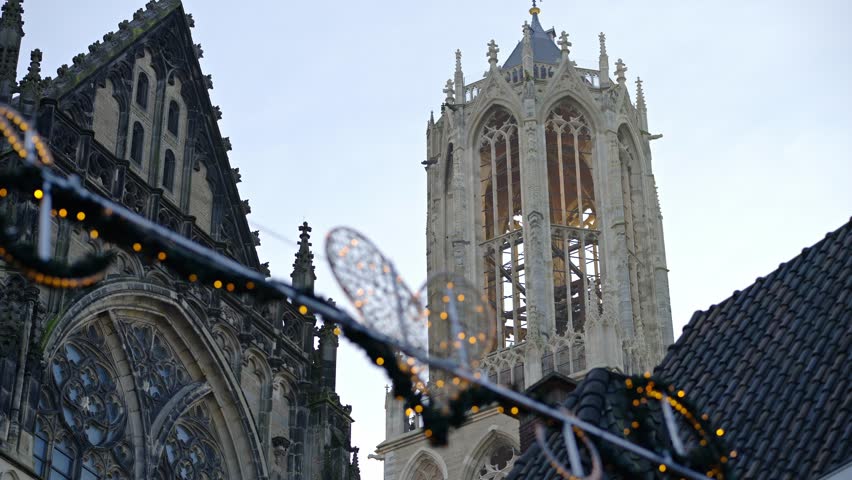 Gothic cathedral and historic church tower, Dom tower, with festive holiday lights in European city Utrecht during winter evening