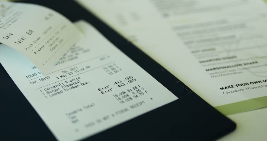 Cafe check with dish prices and final amount for provided services of public place. Bill with digits put on hard bill folder placed on restaurant paper menu