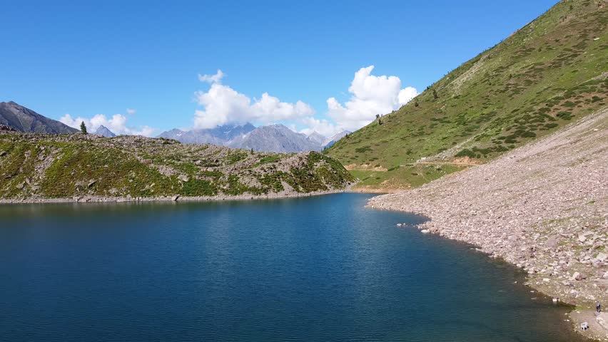 Deep blue Rama lake reflecting the surrounding mountains in Rama Valley, Khyber Pakhtunkhwa province, Pakistan. Aerial Dolly Back