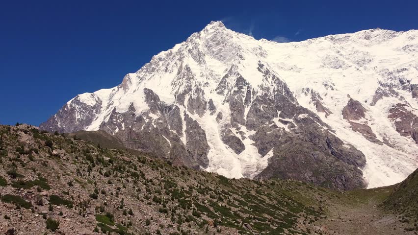 Nanga Parbat, the ninth highest mountain, towers over Rupal Valley in Gilgit Baltistan, Pakistan, draped in snow and ice. Aerial Rising Shot
