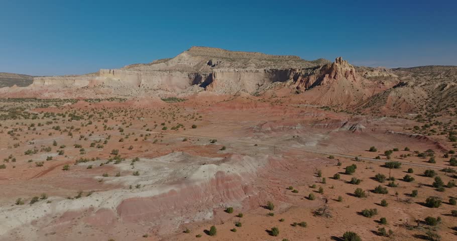 Vast desert landscape with rocky formations and dirt paths under a bright blue sky in New Mexico