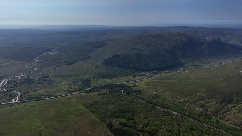 Barnesmore Gap, County Donegal, Ireland, June 2023. Drone panoramic establishing overview above mountain peaks, connecting passage way with long road through boglands and forest on summer day