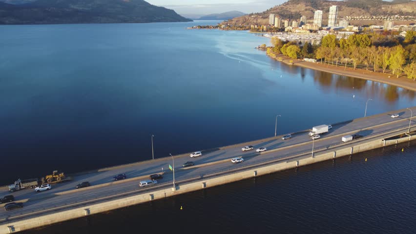 Arriving in Kelowna, BC, Canada. Downtown Waterfront Beach Pan of Bridge. British Columbia, Summer Sunset. Calm Okanagan Lake. City Park, Pan North to South From Lakecountry to The Mission - Penticton