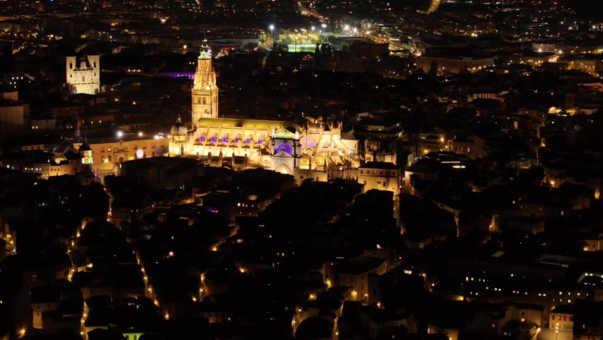 70mm drone filming of the city of Toledo at night, we see its cathedral as a central element very illuminated, since it is an emblematic icon, magic is created through its night streets. dazzling
