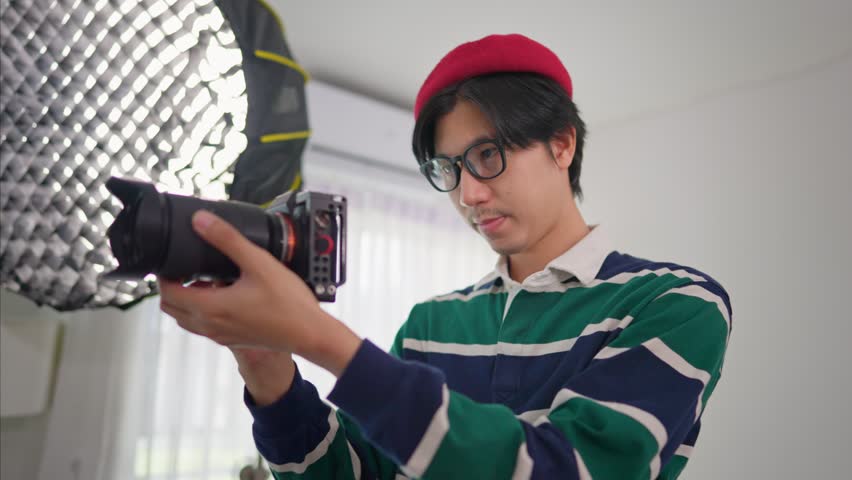 Asian cameraman shooting woman model with backdrop in photography studio. Attractive professional photographer taking beautiful pictures using techniques to create images for advertisement or movies.