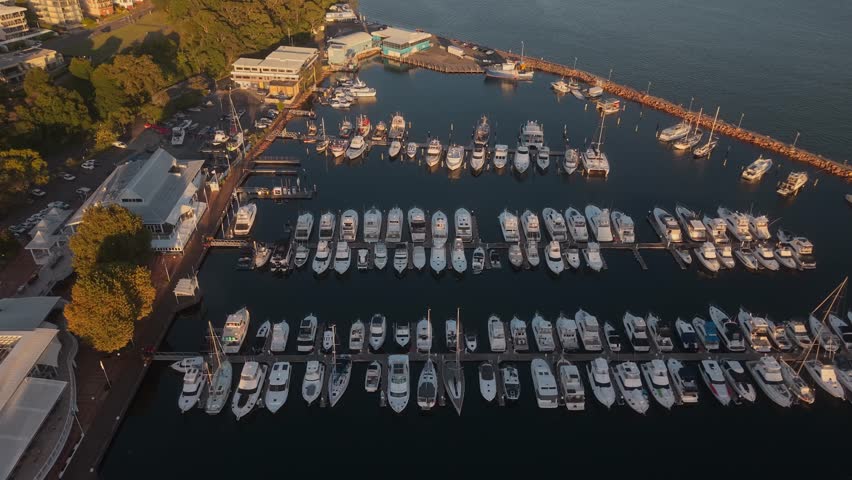 Aerial angled tracking right of Nelson Bay Marina with boats docked along the waterfront in New South Wales, Australia