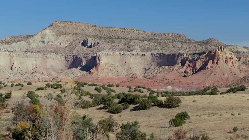 A vast desert landscape with colorful cliffs and distant mountains in New Mexico