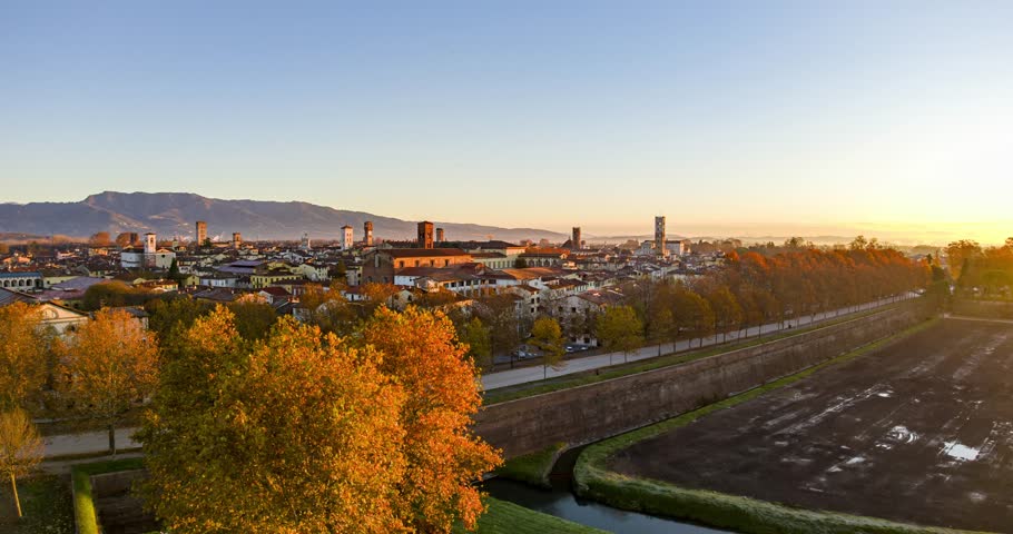 Aerial timelapse view of the medieval walls surrounding Lucca, a historic city in Tuscany, Italy, during a beautiful sunrise in autumn