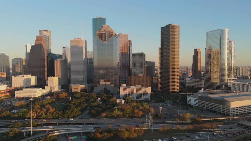 Breathtaking and stunning aerial view of downtown Houston, Texas at sunset, beautifully showcasing iconic skyline and vibrant urban life framed against a picturesque and colorful golden backdrop