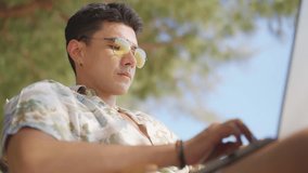 Asian man remote working corporate business on laptop computer during travel the beach on summer holiday vacation. Workation, work from anywhere with wireless technology and digital gadget device. - Powered by Shutterstock - Get 15% off with code: PIKWIZARD15