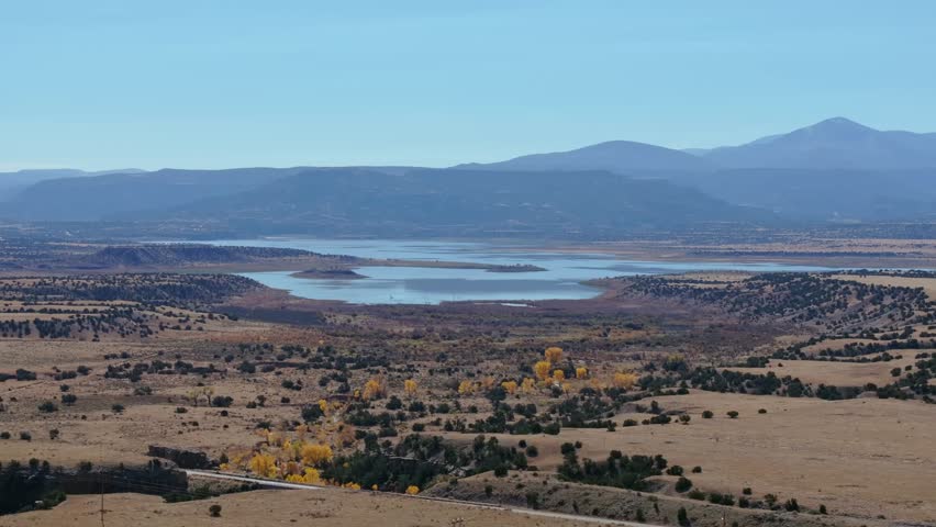 Abiquiu Lake landscape with mountain backdrop, wide view showing fall foliage