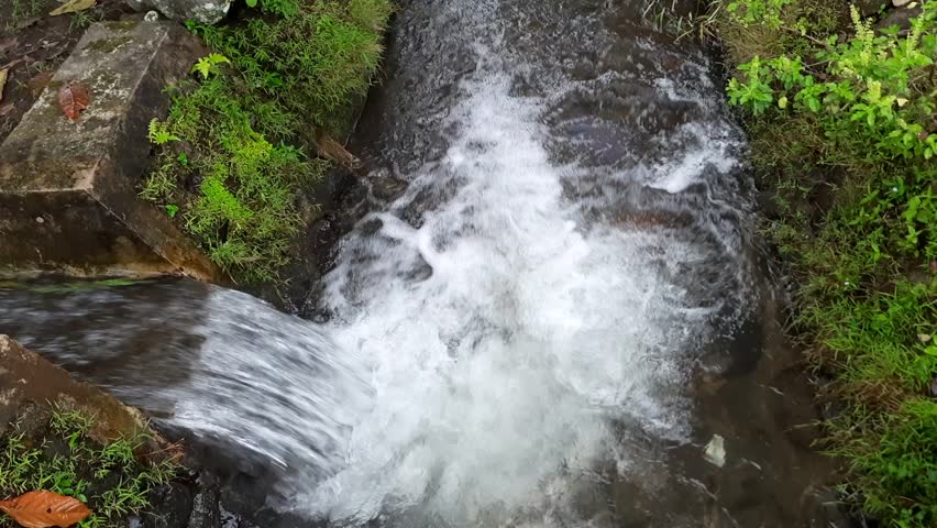 Clear water flowing through an irrigation canal in a rural village, supplying fresh water for rice fields. Essential for sustainable agriculture and efficient water management