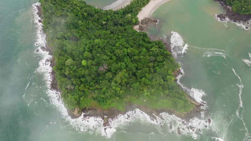 This aerial view of Playa Manuel Antonio in Costa Rica showcases its lush greenery and sandy beaches, revealing a captivating tropical paradise
