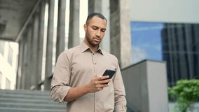Serious thoughtful business man entrepreneur, employee, freelancer, walks down the stairs and uses the phone. pensive male looking at smartphone browsing chatting near office building outside outdoors - Powered by Shutterstock - Get 15% off with code: PIKWIZARD15