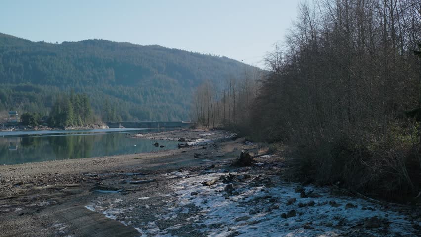 A drone footage of Pitt Lake with lush forested hills and dried vegetation around in autumn