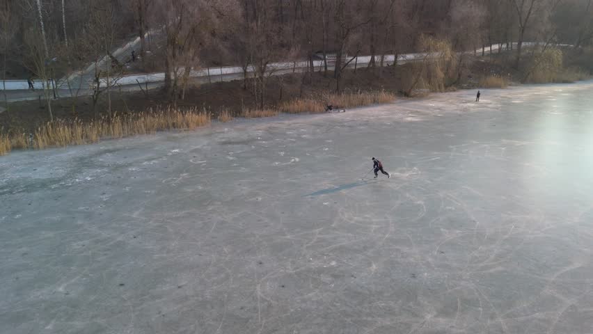 Aerial view of a hockey player skating on a frozen lake in winter