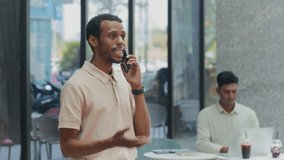 Stab shot of African American businessman talking on mobile phone while his colleague working on laptop in background at outdoor cafe during coffee break - Powered by Shutterstock - Get 15% off with code: PIKWIZARD15