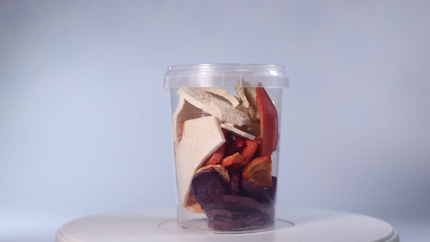 A transparent jar filled with a colorful assortment of freeze-dried fruits and vegetables, including blueberries, cranberries, raspberries, apple slices, pumpkin cubes, and more.