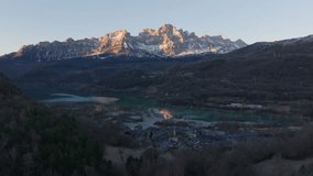 Beautiful sunrise illuminates snowy peaks of Pyrenees mountains reflecting in turquoise lake of Lanuza reservoir with village in Huesca, Spain - Powered by Shutterstock - Get 15% off with code: PIKWIZARD15