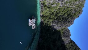 Aerial drone view of Coron Island’s dramatic cliffs, tropical greenery, and idyllic turquoise waters, Philippines. Descending shot towards dock house. Vertical video. - Powered by Shutterstock - Get 15% off with code: PIKWIZARD15