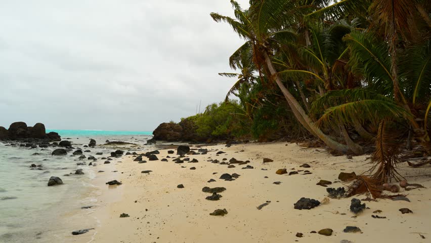 The volcanic rocks next to the sandy beach and coral reefs of Aitutaki Atoll.
