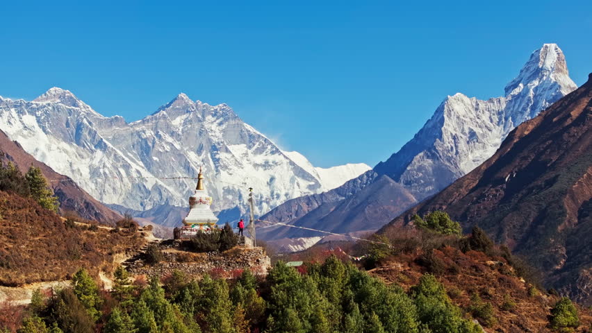 Majestic Mount Everest towers over a serene landscape, observed by a tourist from a traditional buddhist stupa, showcasing the beauty and spirituality of the Himalayas