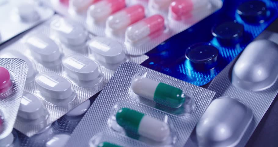 Detailed closeup view of vividly vibrant pink capsules and various pills arranged neatly in blister pack