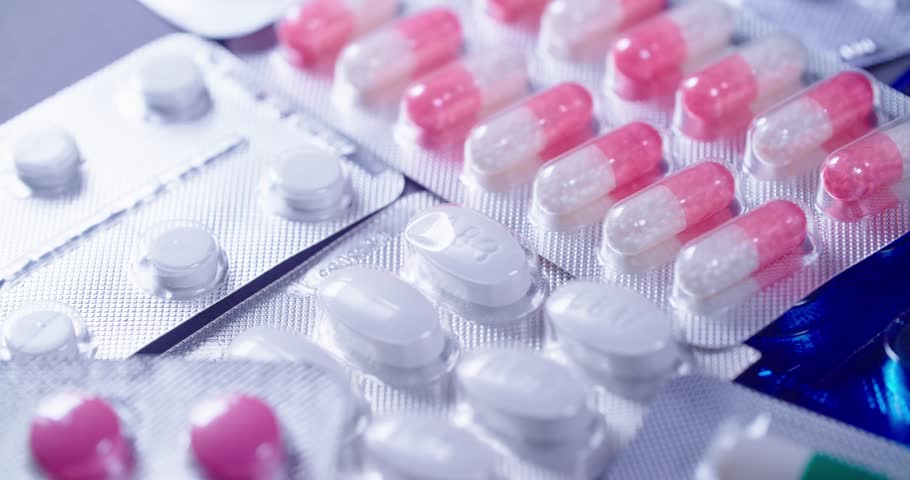 Detailed closeup view of vividly vibrant pink capsules and various pills arranged neatly in blister pack