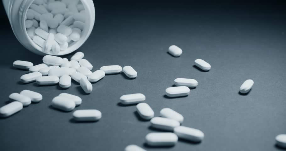 Сlose-up of vitamin pills and bottles on a dark background slowly fly out of the jar on to the table