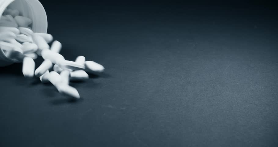 Сlose-up of vitamin pills and bottles on a dark background slowly fly out of the jar on to the table