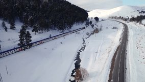 Aerial view of a train moving through a snow-covered forested valley. The winding tracks offer a peaceful journey through nature, blending transportation with the serene beauty of winter. - Powered by Shutterstock - Get 15% off with code: PIKWIZARD15