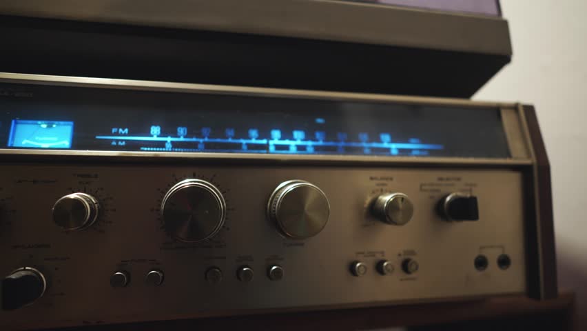 Hand turns illuminated tuning frequency dial on retro radio CLOSE-UP